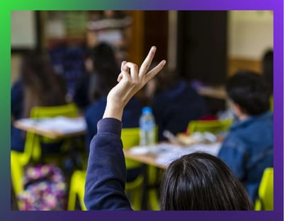 A picture of a classroom where one student raises a hand.